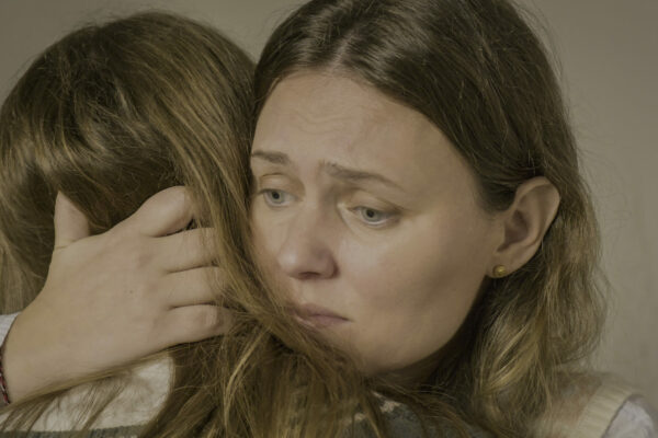 An emotional embrace between two people, focusing on one's concerned expression.