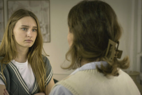 Two women having a serious conversation, one looking concerned while the other is seen from behind.
